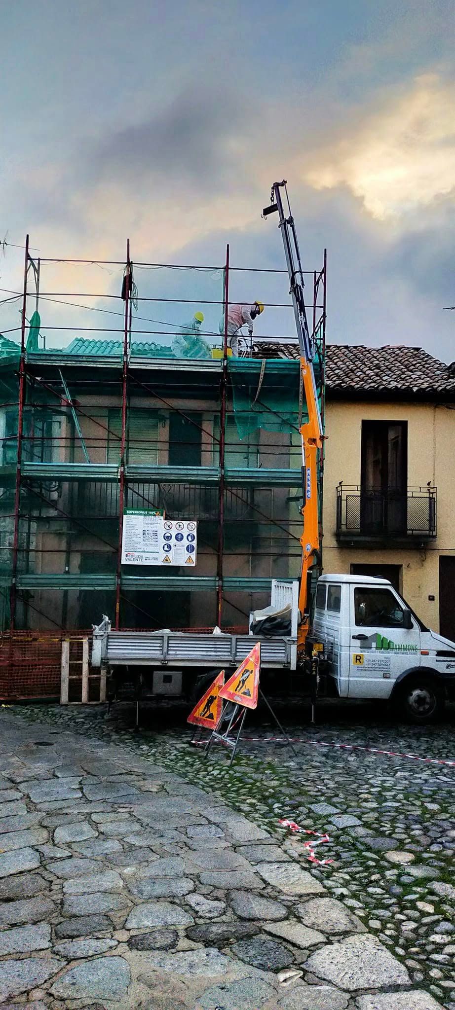 Strada di mattoni accanto a un edificio con impalcature, con un camion bianco parcheggiato davanti al crepuscolo.