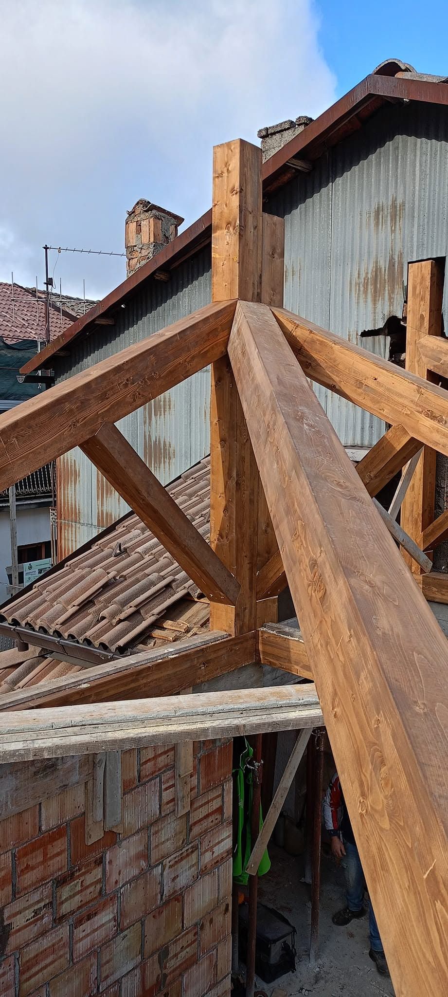 Sotto un cielo azzurro, travi metalliche arrugginite attraversano un edificio in mattoni parzialmente demolito.