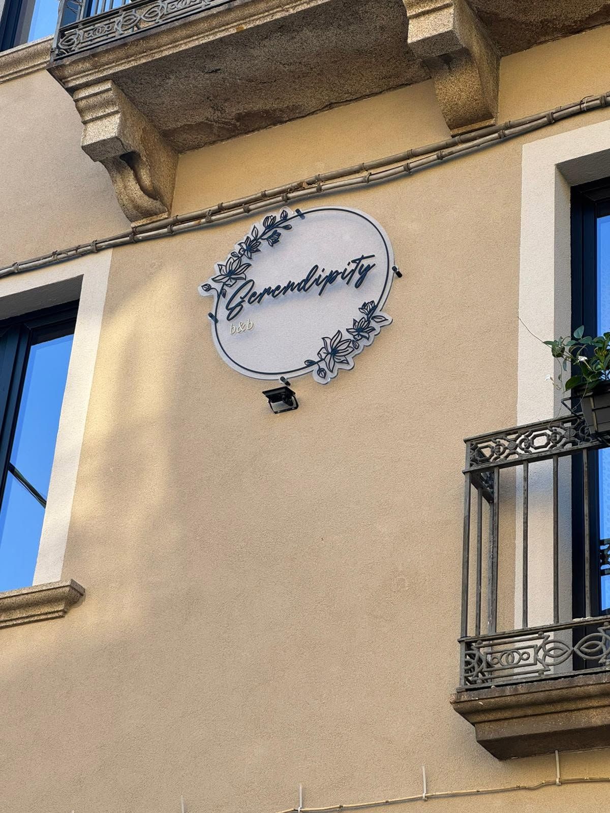 Muro dell'edificio con insegna rotonda e finestre con cornice blu su una facciata beige.