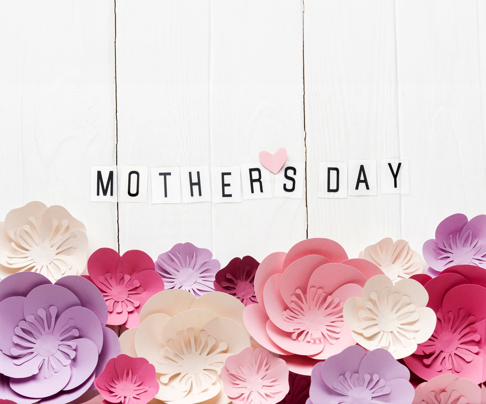 A mother 's day card with paper flowers on a white wooden background.