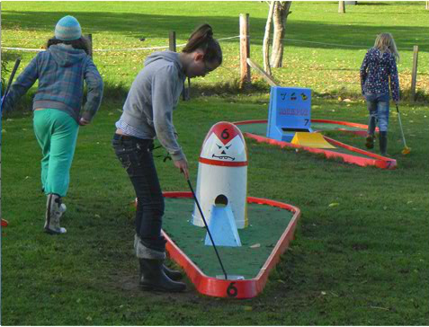 A woman is playing a game of mini golf in a park