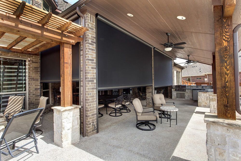 Covered outdoor patio with seating, ceiling fans, and a large black retractable screen