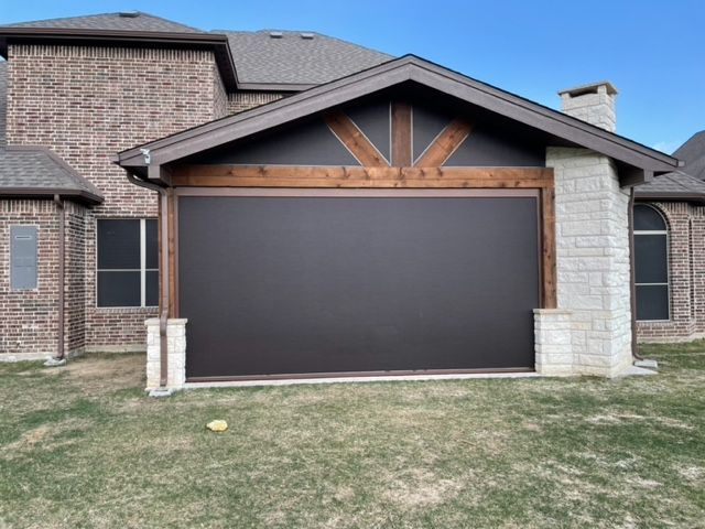 Brick house front with a large dark garage door and small lawn in front