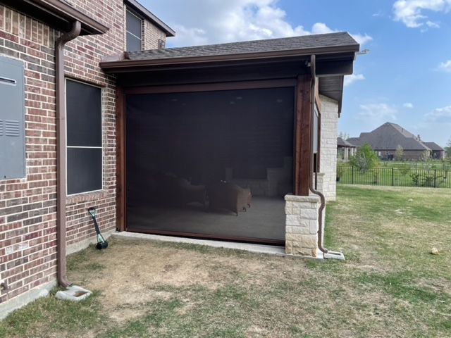 Brick house exterior with a screened patio enclosure and small grassy yard