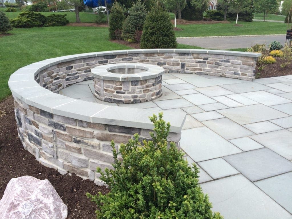 Curved stone patio with built-in circular seating wall in a landscaped garden