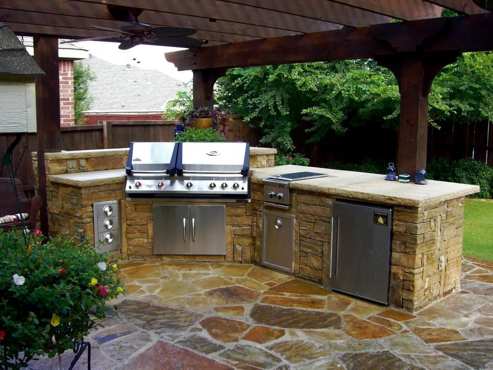 Outdoor stone patio with built-in stainless steel grill, cabinets, and pergola