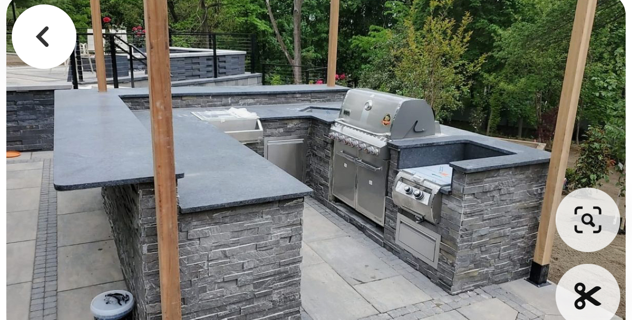 Outdoor stone patio with built-in stainless steel grill, sink, and black countertops