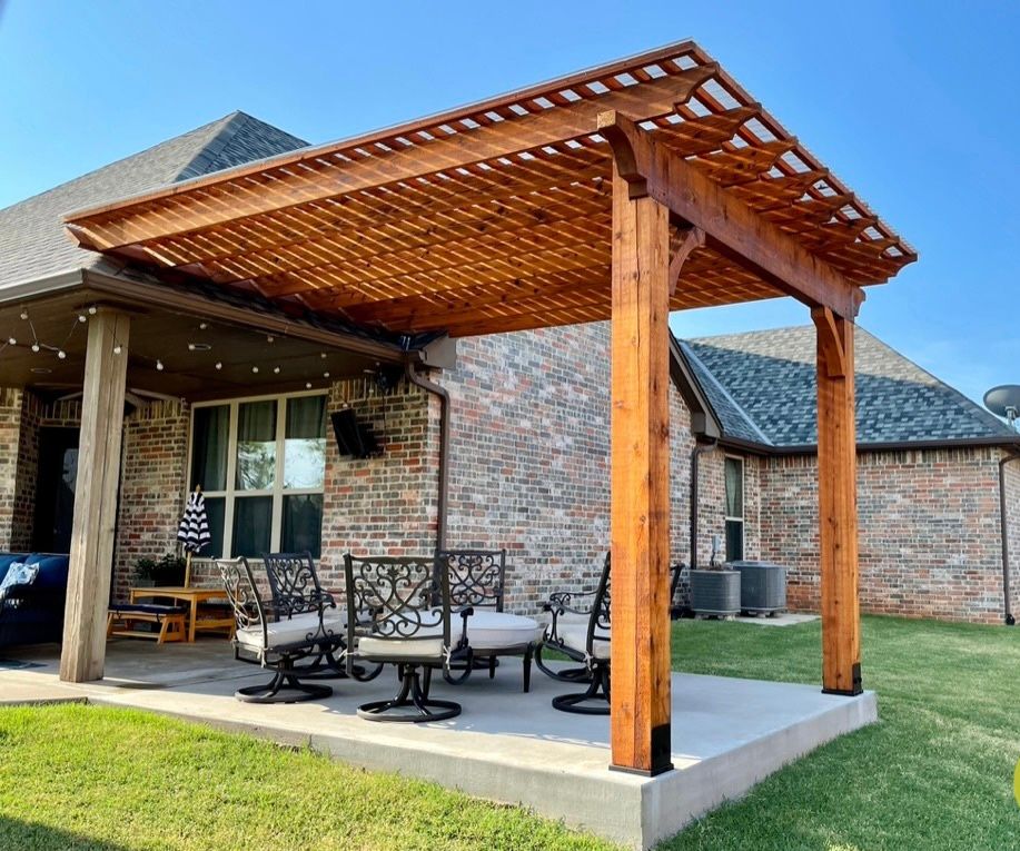 Backyard patio with a wooden pergola, metal furniture, and brick house exterior.