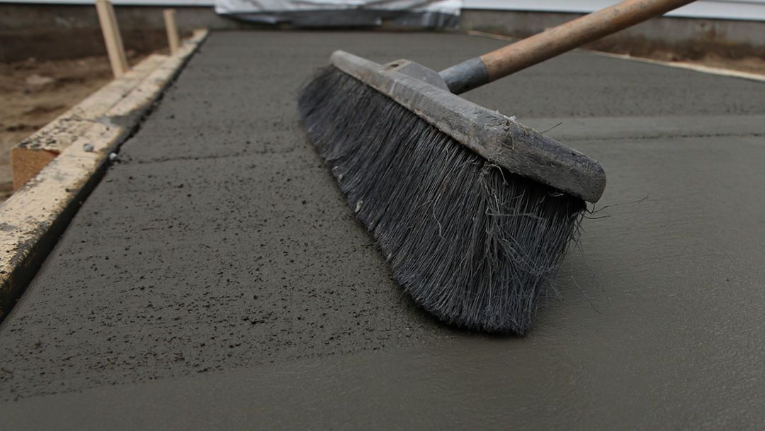 Push broom smoothing fresh gray concrete on a construction site
