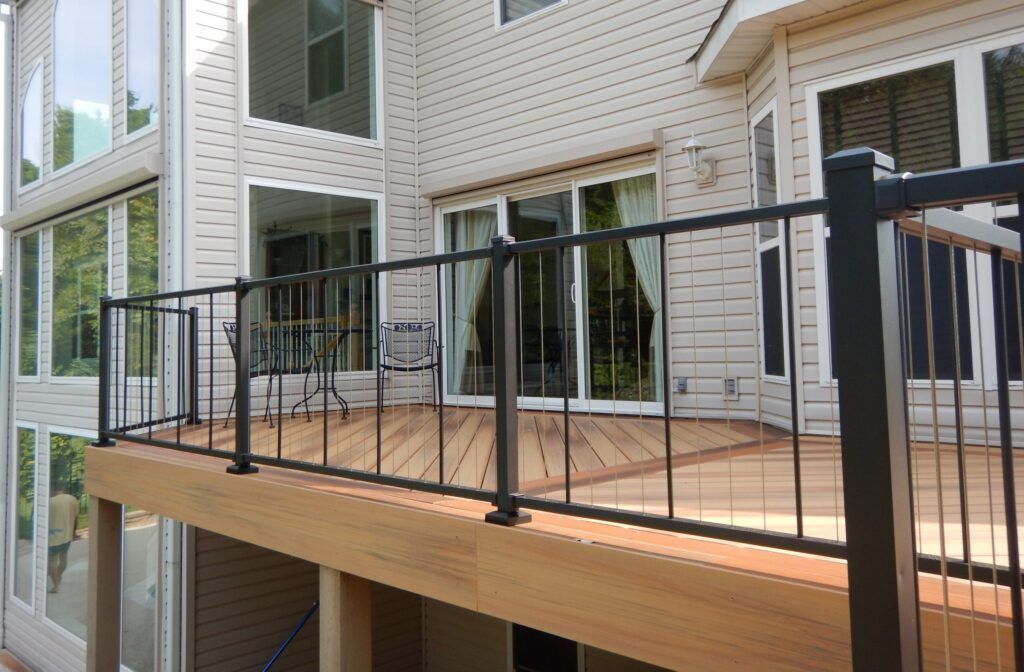 Wooden deck with black metal railing attached to the side of a house