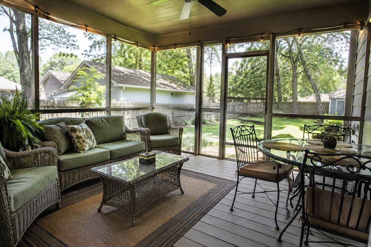 Screened porch with wicker seating, glass coffee table, and dining set overlooking a green backyard.