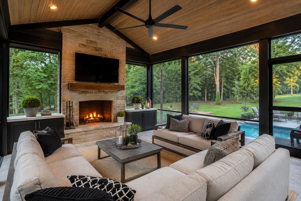 Cozy modern screened porch with sectional sofas, fireplace, and pool view through large windows