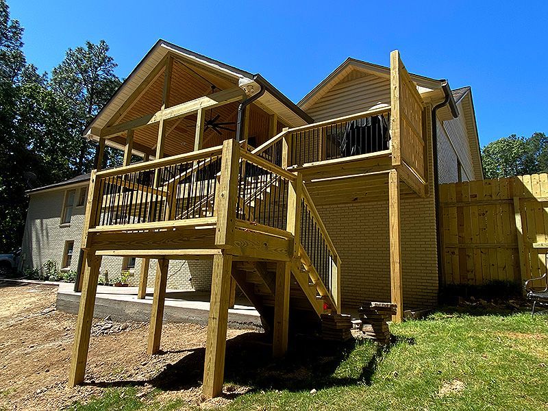 Wooden cabin porch with stairs and railing in a sunny wooded yard