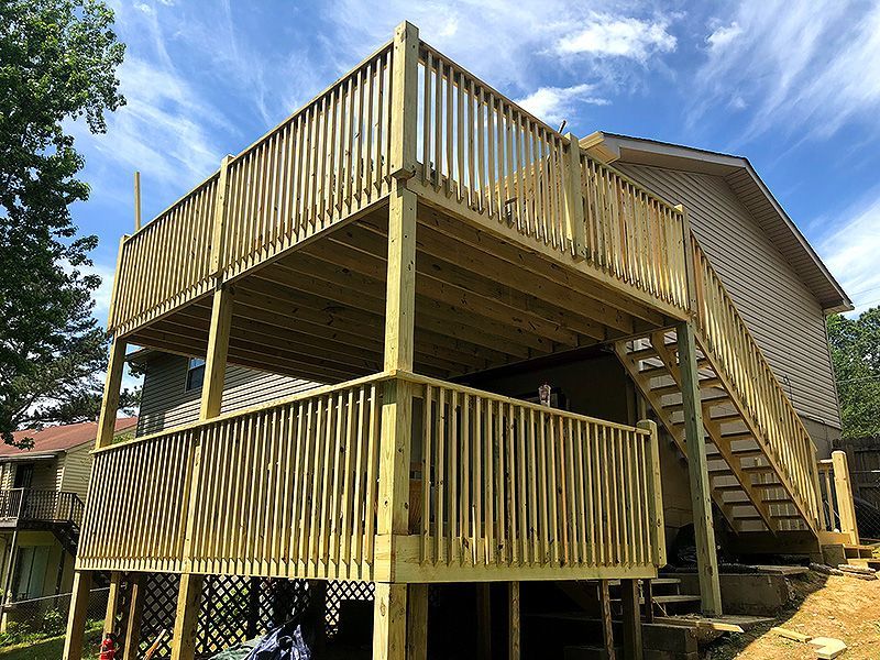 Wooden multi-level deck and staircase attached to a house on a sunny day