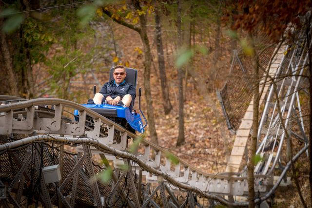 Person enjoying a solo ride on a mountain coaster in a forested area