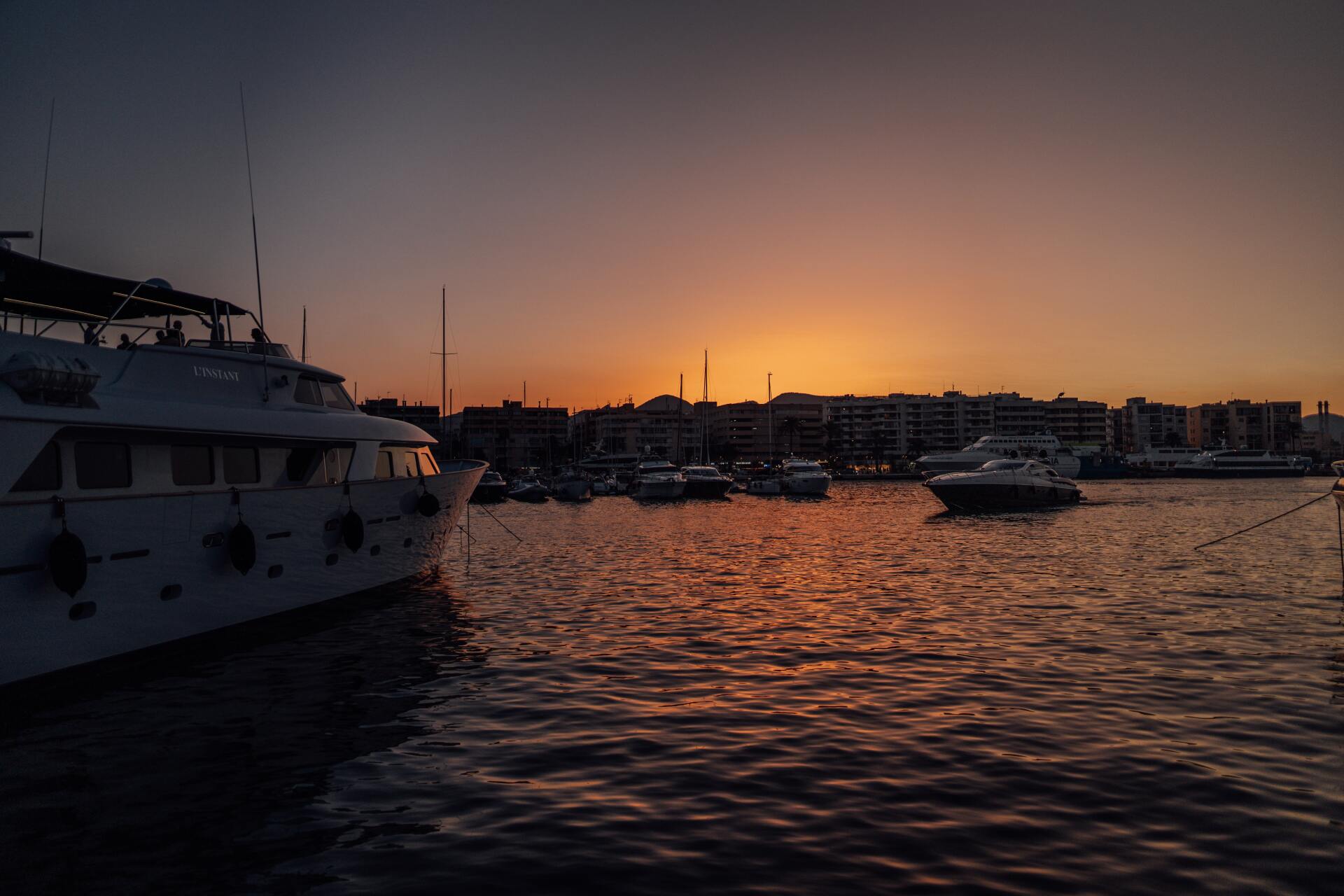 Docks and yachts at sunset with deep orange and purple hues reflecting on the water