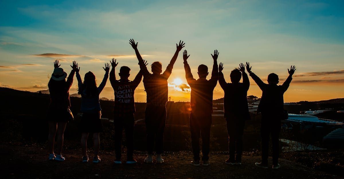 a group of people celebrating under the evening sunset
