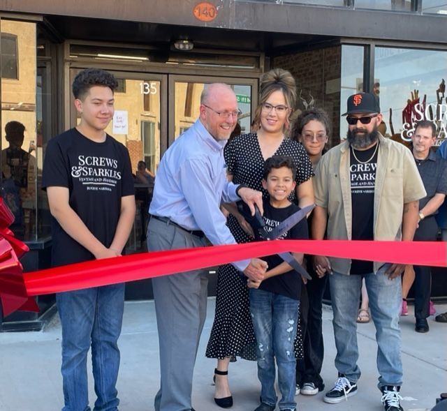 A group of people standing in front of a store that says screws & sparks