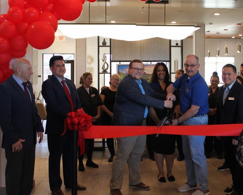 A group of people are cutting a red ribbon