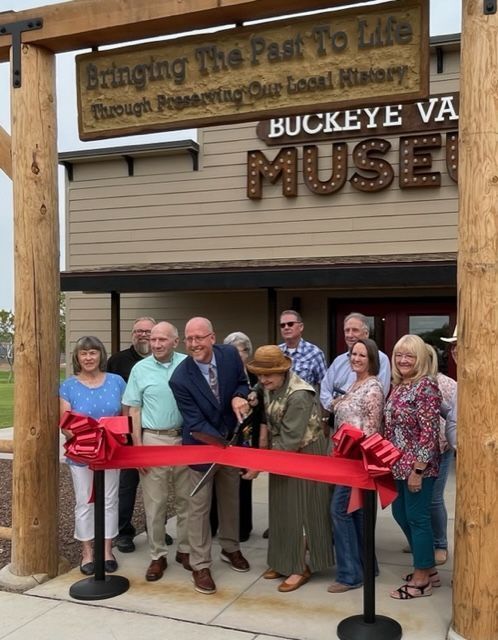 A group of people cutting a red ribbon in front of the buckeye va museum