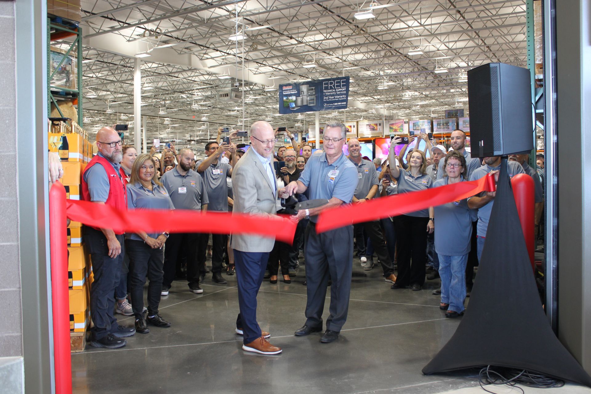 A group of people are cutting a red ribbon in a store.