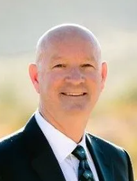 A man in a suit and tie is wearing glasses and a red tie.
