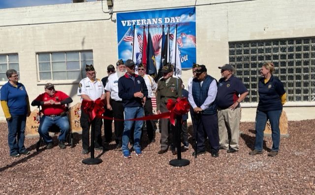 A group of people are standing in front of a sign that says veterans day