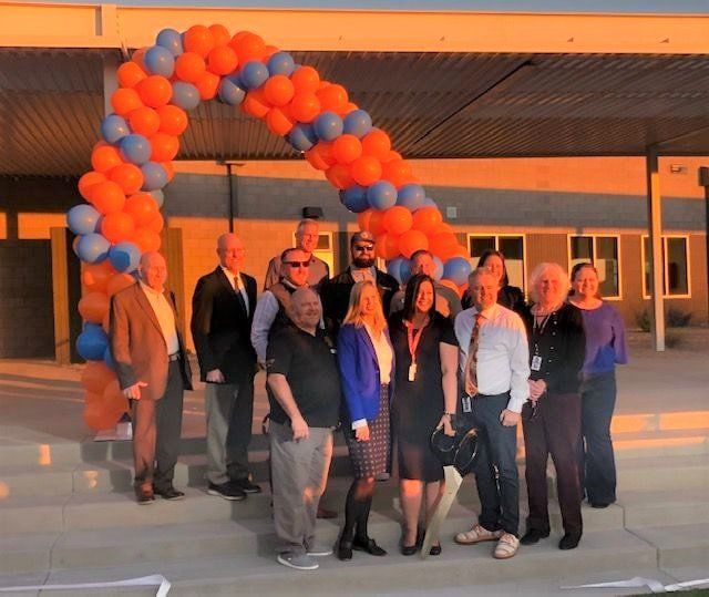 A group of people standing in front of an orange and blue balloon arch