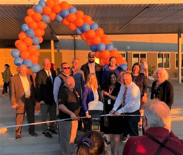A group of people cutting a ribbon with balloons in the background
