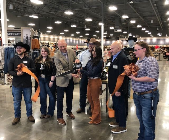 A group of people are cutting a ribbon in a store