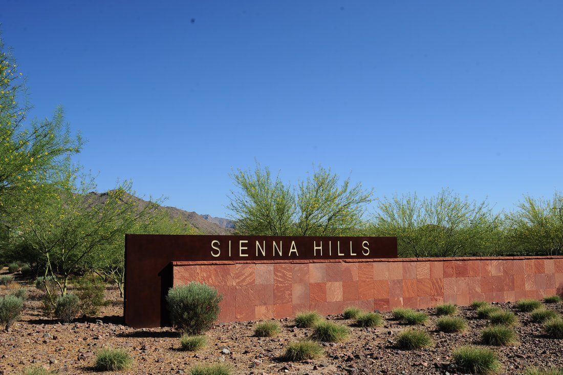 A sign for sienna hills is sitting in the middle of a desert.