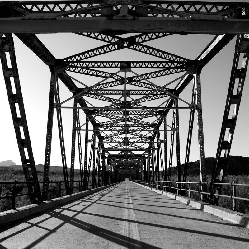 A black and white photo of a bridge over a road