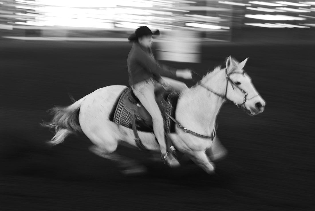 A person is riding a white horse in a black and white photo.