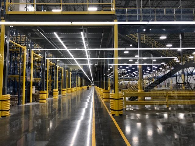 A large warehouse with a lot of shelves and a lot of lights.