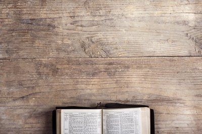 An open bible is sitting on a wooden table.