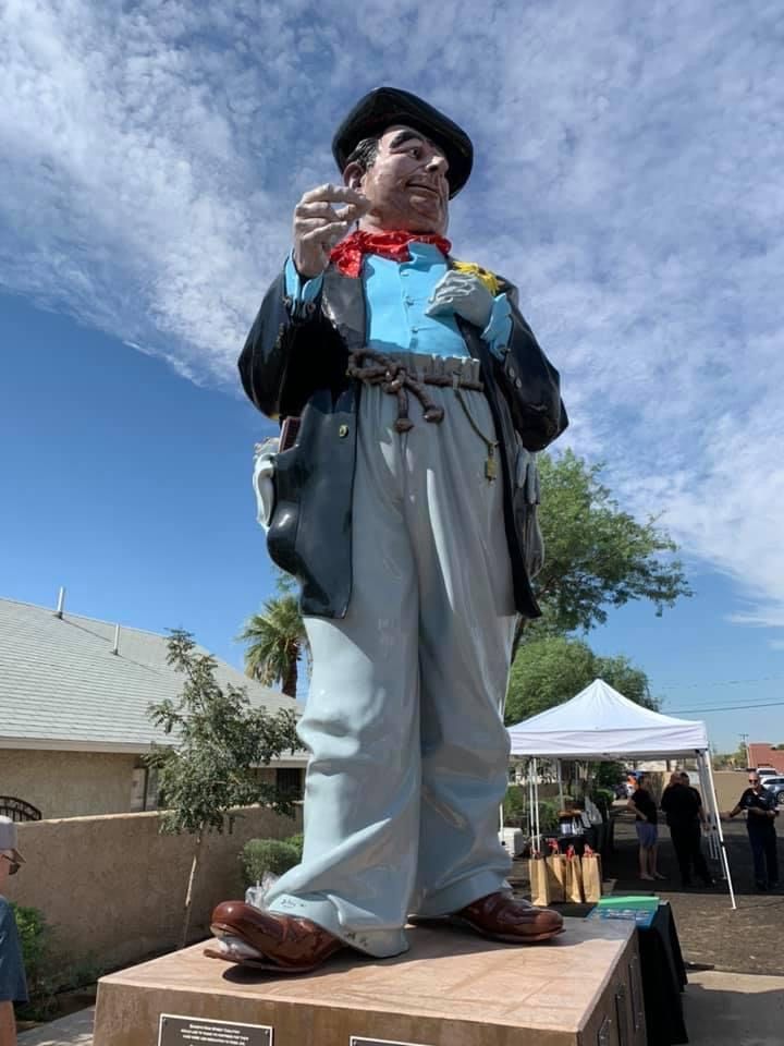 A statue of a man in a suit and hat is standing on a pedestal.