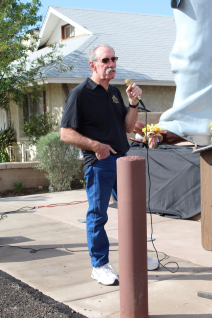 A man speaking into a microphone in front of a house