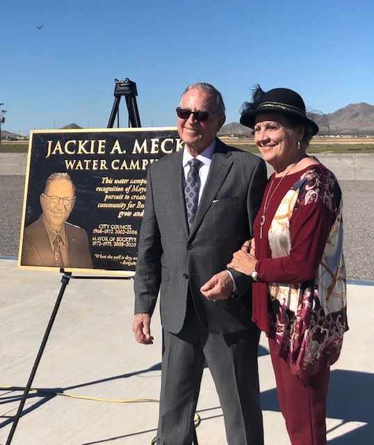 A man and woman standing in front of a sign that says jackie a. mech water camp