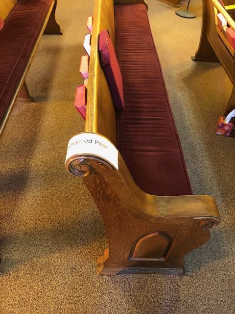 A row of wooden benches in a church with red cushions.
