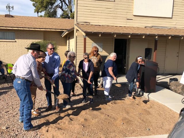 A group of people are digging in the dirt in front of a building.