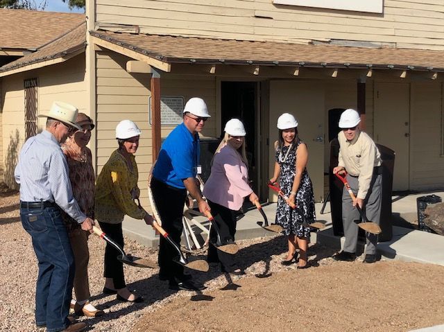 A group of people wearing hard hats are digging in front of a building.