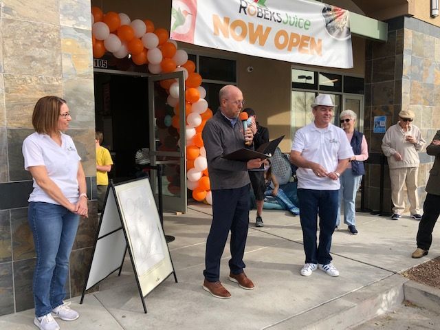 A man is giving a speech in front of a store that is now open