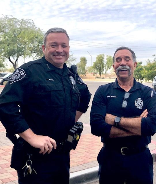 Two police officers are standing next to each other on the side of the road.