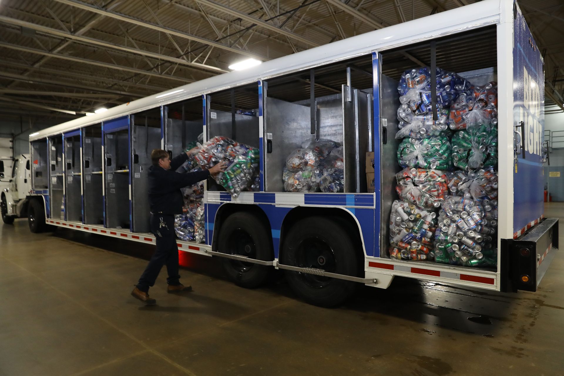a man is loading bottles into a truck in a warehouse .