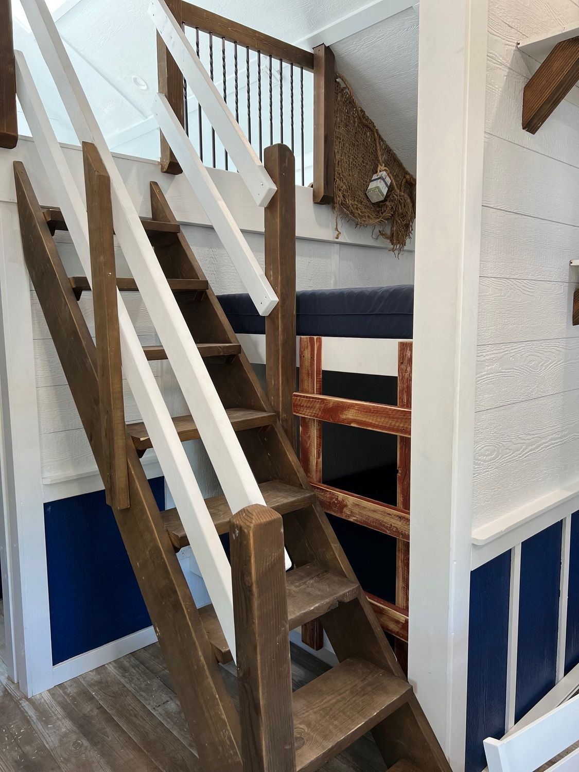 Wooden stairs with white railing lead to an upper level, blue and white interior.