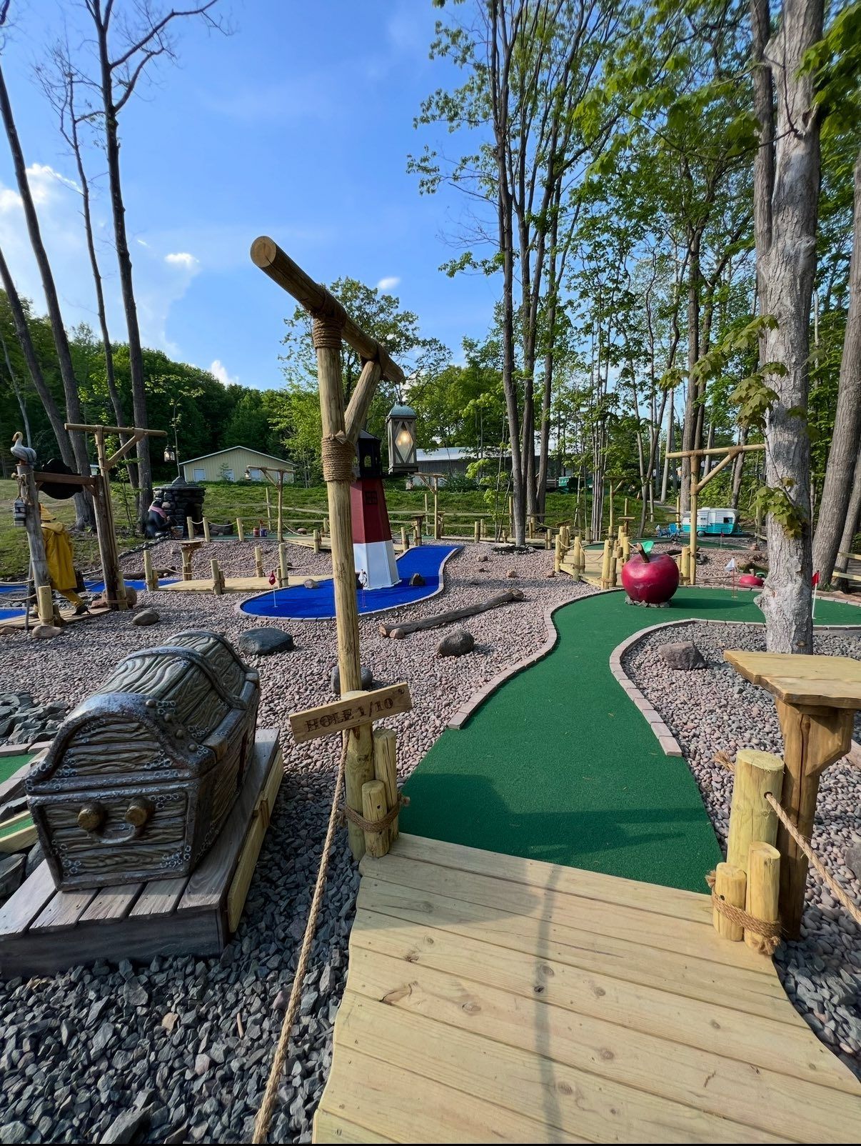 Miniature golf course with wooden features and green turf paths.