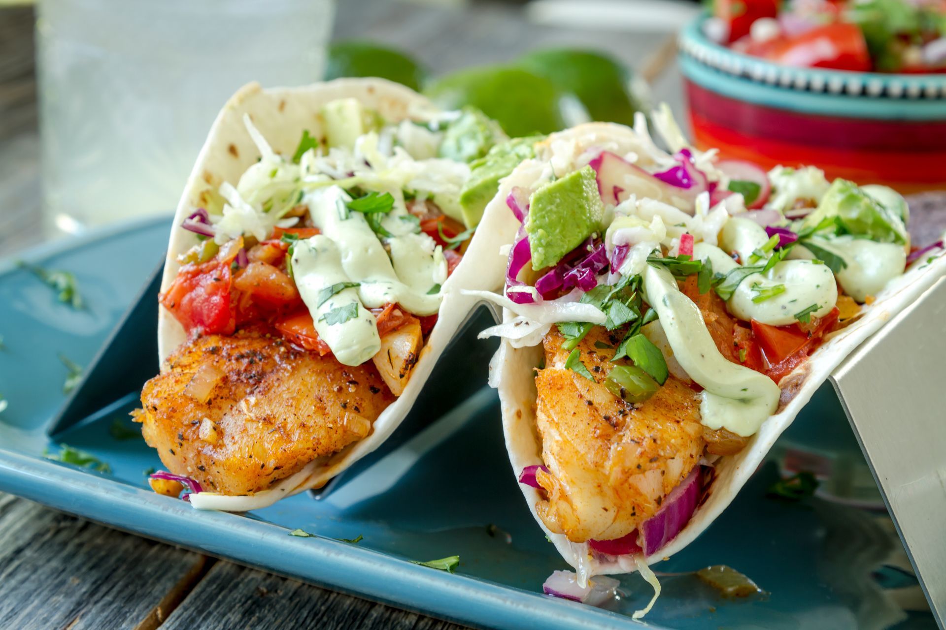 Two fish tacos with toppings, served on a blue plate.