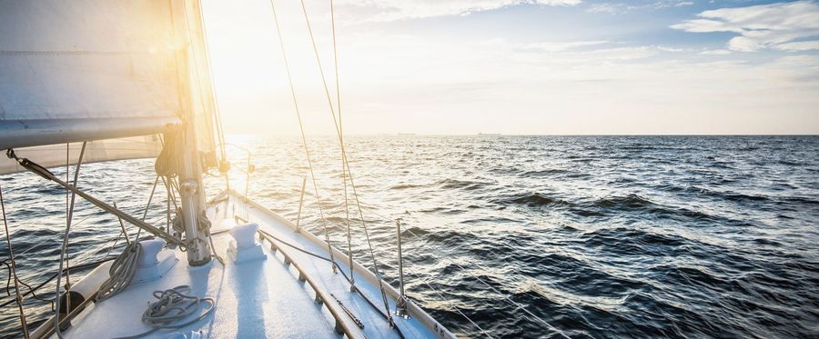 Sailboat sailing on the ocean with sun shining.