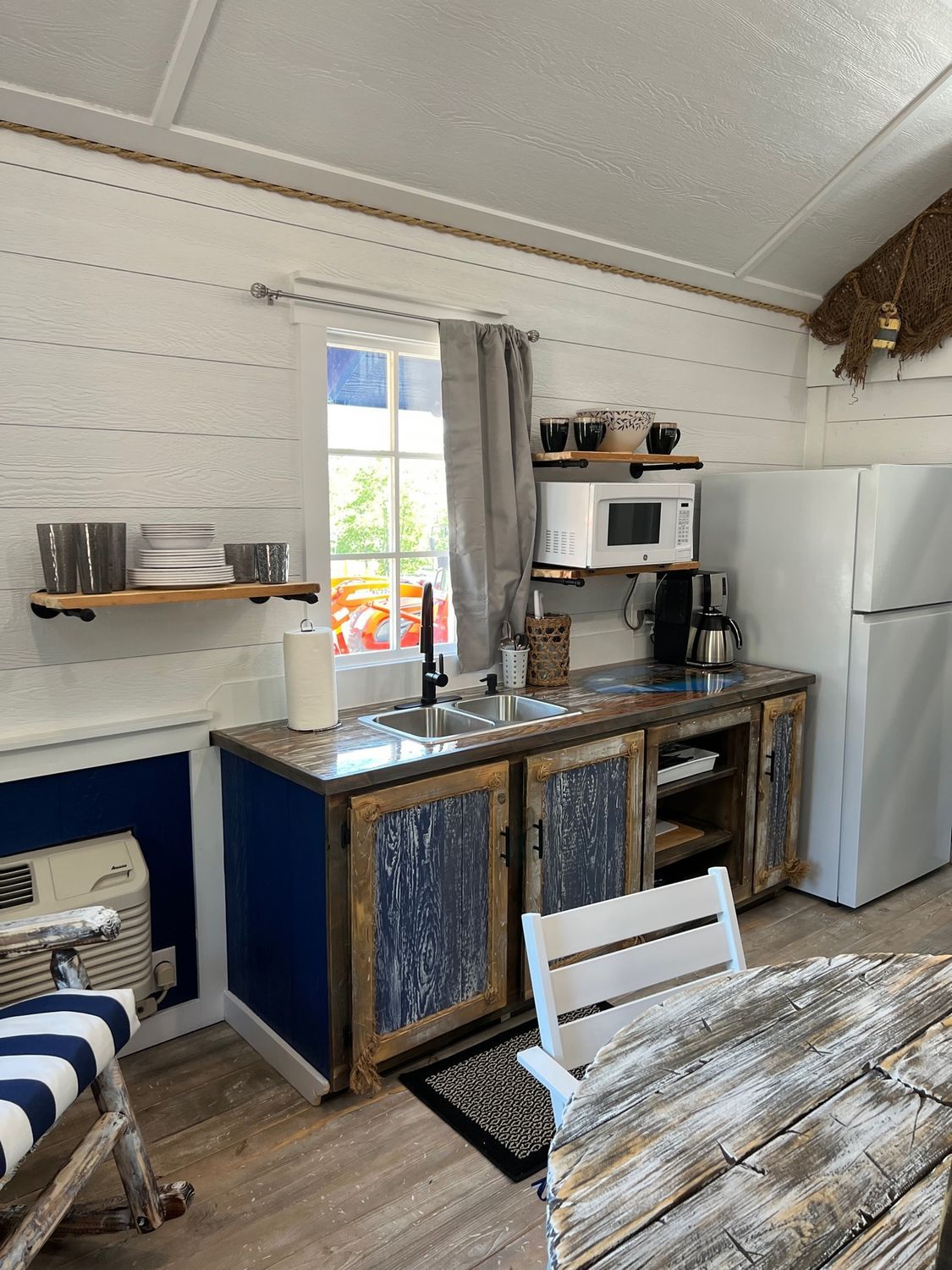 Small kitchen with a sink, microwave, refrigerator, and wooden cabinets.