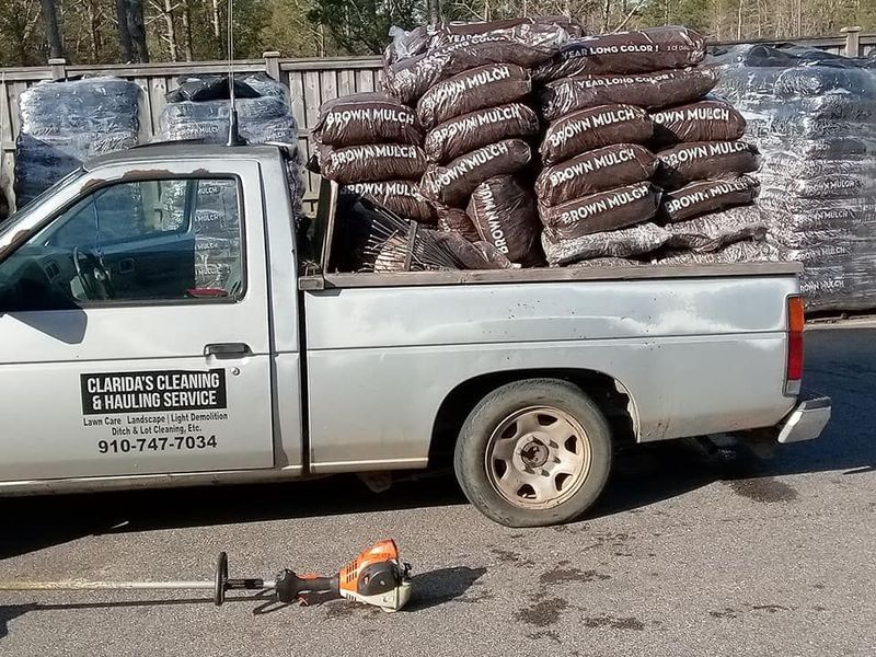 White pickup truck loaded with brown mulch bags; a chainsaw lies on the pavement in front.